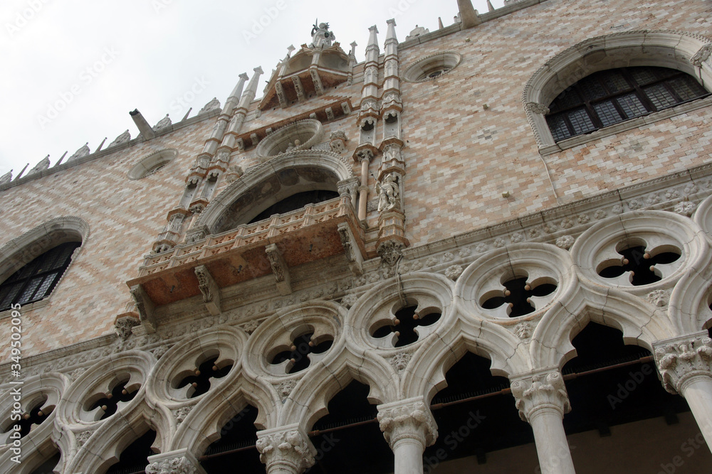 Part of facade of Doge's palace with columns, windows, sculptures in Venice.