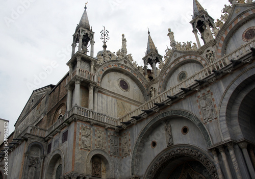 Marble facade of St. Mark's Cathedral with mosaics, sculptures in Venice in sunny summer day.