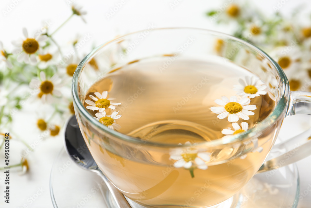 Fresh chamomile tea in cup on white table, closeup Fresh chamomile tea in cup on white table, closeup