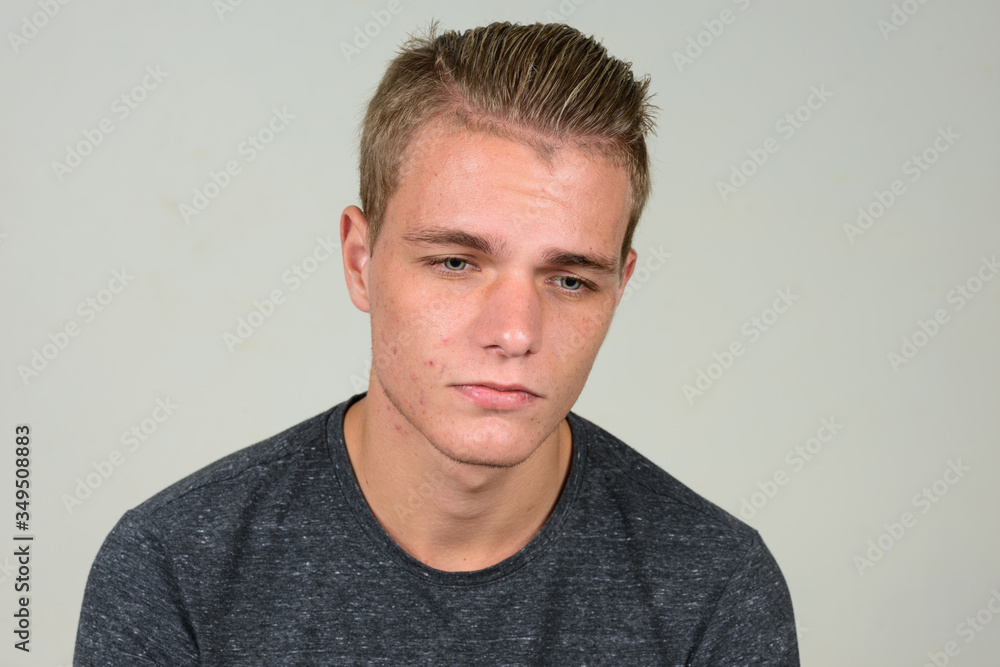 Fototapeta premium Face of stressed young man with blond hair thinking and looking down