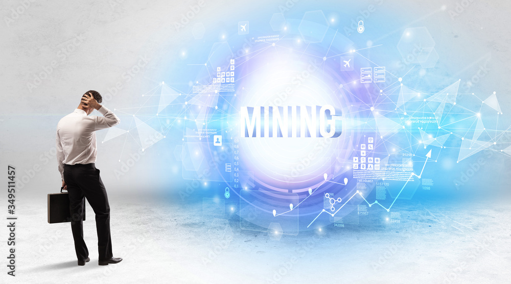 Rear view of a businessman standing in front of MINING inscription, modern technology concept Rear view of a businessman standing in front of MINING inscription, modern technology concept