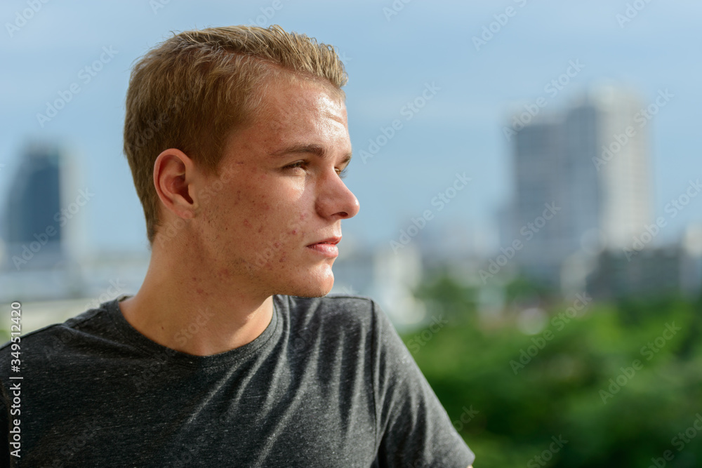 Closeup profile view of young handsome man with blond hair outdoors Closeup profile view of young handsome man with blond hair outdoors