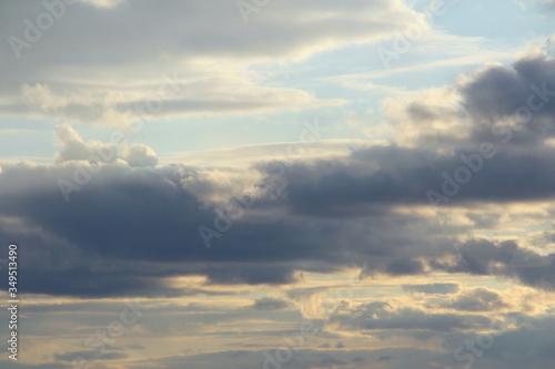 Clouds in the blue sky at sunset or dawn backlit by the sun. Place for text and design.