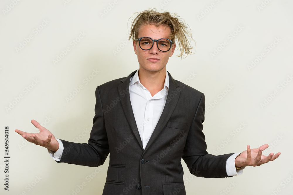 Stressed young blond businessman with eyeglasses shrugging shoulders Stressed young blond businessman with eyeglasses shrugging shoulders