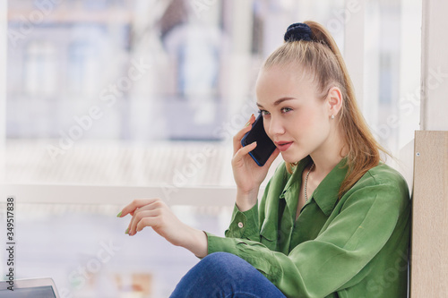Young beautiful woman sits with a smartphone