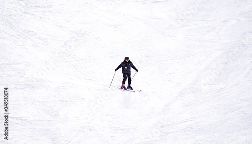 Full length of skier skiing on fresh powder snow. Man skier running downhill on sunny Alps slope
