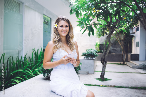 Cheerful woman with smartphone looking at camera and smiling Free Download Cheerful woman with smartphone looking at camera and smiling - GFXLoad