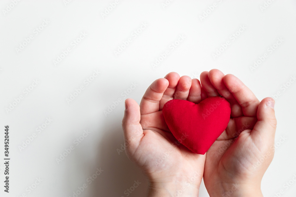 Close up child hand holding red heart on light background top view with copy space Close up child hand holding red heart on light background top view with copy space