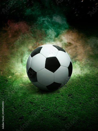 Traditional soccer ball on soccer field. Close up view of soccer ball  football  on green grass with dark toned foggy background. Selective focus