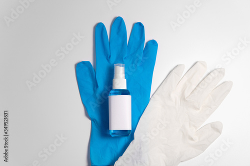 Top down view blue alcohol liquid for medical purpose and Anticoronavirus COVID-19 (Ethanol or ethyl alcohol) in a plastic spray bottle with blank label on blue disposable glove white color background photo