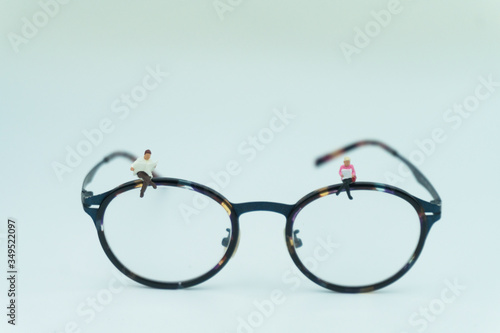 Miniature people.businessman and businesswoman sitting and reading newspaper and document on Glasses