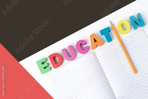 " EDUCATION " Multicolored Wooden Letters with Orange Pencil Instead ' I ' Letter and Paper Book on White Background, Learning for Kids, Copy Color Space
