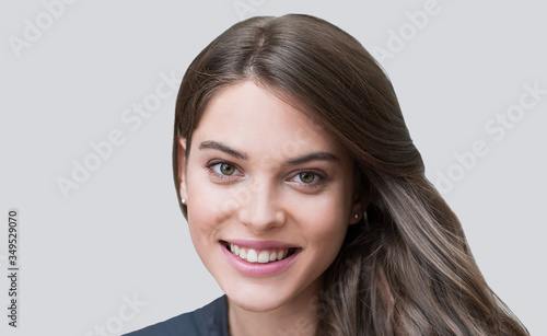 	
Beautiful young woman portrait. Smiling girl looking to camera. Isolated on gray background, beauty, healthy lifestyle, people concept
 photo