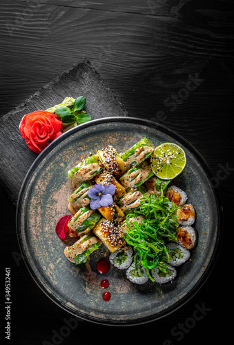 set of sushi roll with salmon, avocado, cream cheese, cucumber, rice, caviar, eel, tuna in plate on black wooden table background