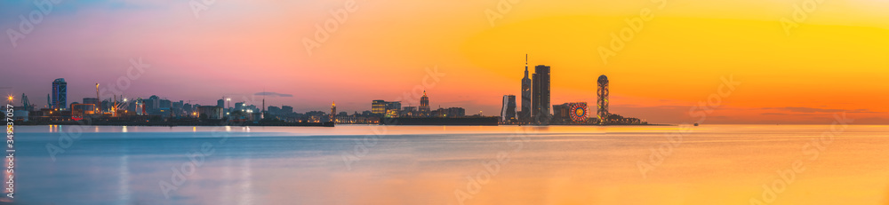 Batumi, Adjara, Georgia. Skyline Of Resort Town At Sunset Sunrise. Bright Orange Evening Sky. View From Sea To Cityscape With Modern Urban Architecture, Skyscrapers And Tower. Golden Hour. Panorama