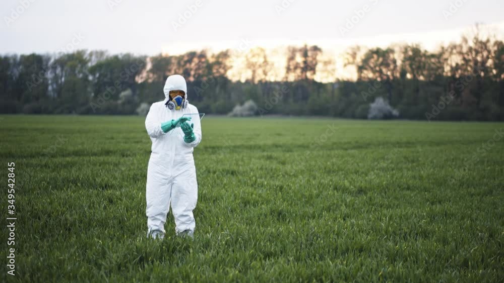 Ecology expert in protective anti-viral suit white hazmat using digital tablet monitoring field soil condition rural harvest at sunset. Farming technology. Innovations. Ecology expert in protective anti-viral suit white hazmat using digital tablet monitoring field soil condition rural harvest at sunset. Farming technology. Innovations.