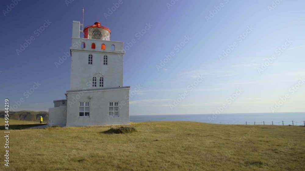 Large white lighthouse on Cape Dyrholaey. Lighthouse building on the edge of a cliff Large white lighthouse on Cape Dyrholaey. Lighthouse building on the edge of a cliff