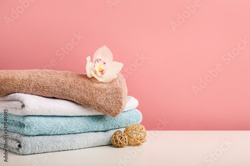 Stack of bath towels with white orchid flower on pink background © LumenSt
