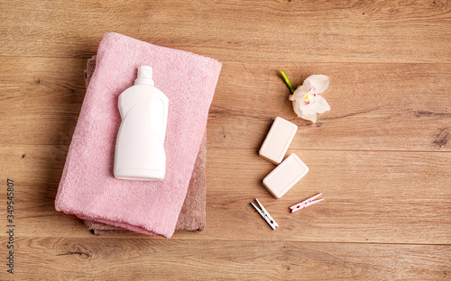 Bath towels, detergent, soap and clothespins on wooden surface photo