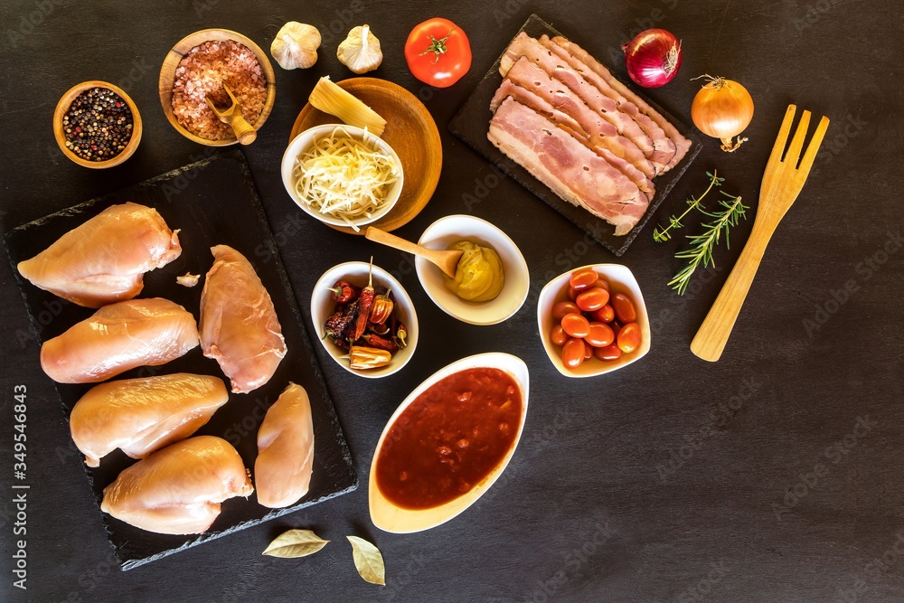 Raw chicken and bacon on the table top. Ingredients for healthy food. Chicken breast with tomatoes. Raw chicken and bacon on the table top. Ingredients for healthy food. Chicken breast with tomatoes.