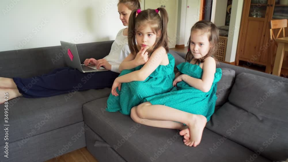 sisters watch tv and mother works remotely on a computer during a pandemic sisters watch tv and mother works remotely on a computer during a pandemic