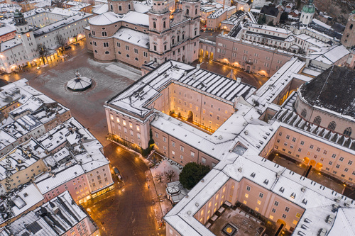 Aerial drone shot of Salzburg dome square and residenzgalerie museum covered in snow during winter at dusk © Davidzfr