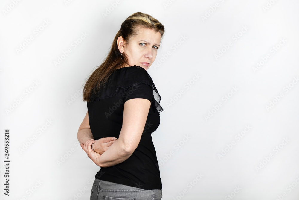 A woman with a tired look holds on to her back because she feels severe pain in her lower back, she often carries little son in her arms and suffers from pain A woman with a tired look holds on to her back because she feels severe pain in her lower back, she often carries little son in her arms and suffers from pain