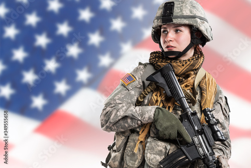 Female in US Army soldier (ISAF) with rifle. Flag of USA on background