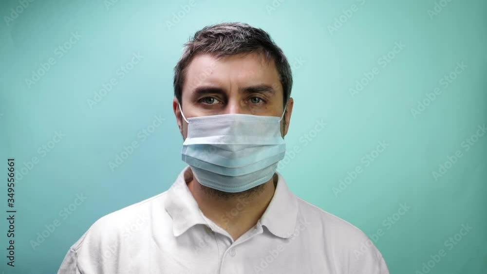 Man take off protective medical mask on blue background Man take off protective medical mask on blue background