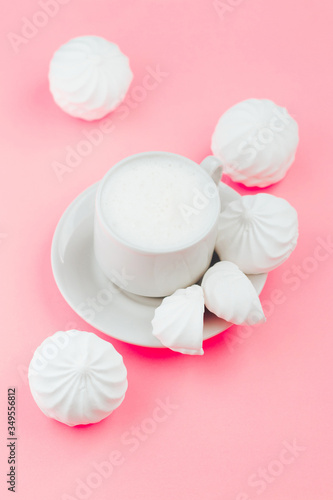 Cup of milk and white marshmallows on pink background close up
