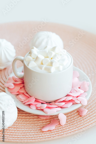 Cappuccino cup decorated with pink hearts and marshmallows on pink background