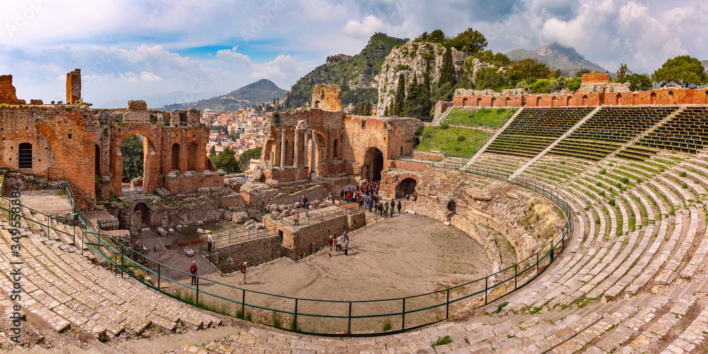 Panoramic view of Ruins of Ancient Greek theatre, Old Town of Taormina and mountain village Castelmola in sunny day, Sicily, Italy