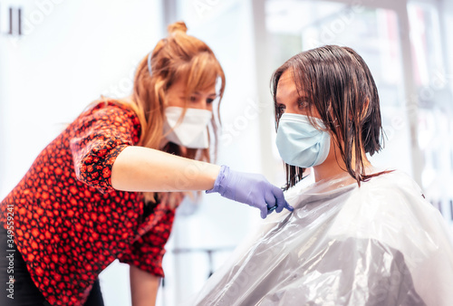 Hairdresser with mask and gloves cutting the client's hair. Reopening with security measures for hairdressers in the Covid-19 pandemic