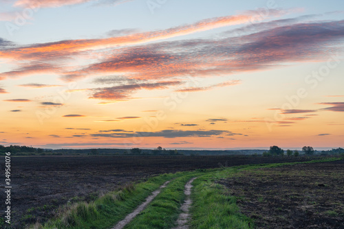 Dirt road in a rural field at sunset