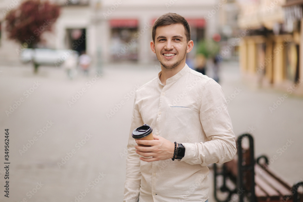Portrait of young man stand in the city with cup of coffee