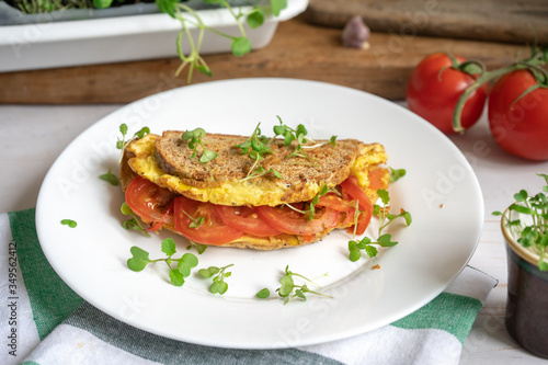 Fried omelette with whole grain bread, tomatoes and microgreens, healthy vegetarian egg toast for breakfast