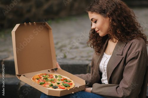 Woman open pizza box outdoors. Female hold open pizza box and smells appetizing
