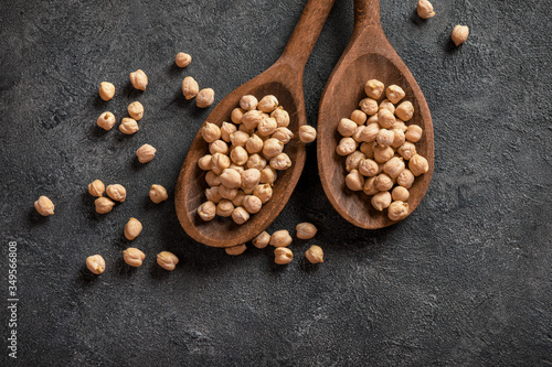 Wooden spoons full of chickpeas on dark background.