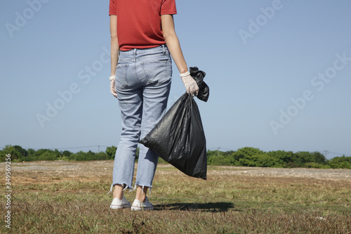 Photo of environmental activist collecting plastic garbage. Volunteer holding plastic bag full of garbage 