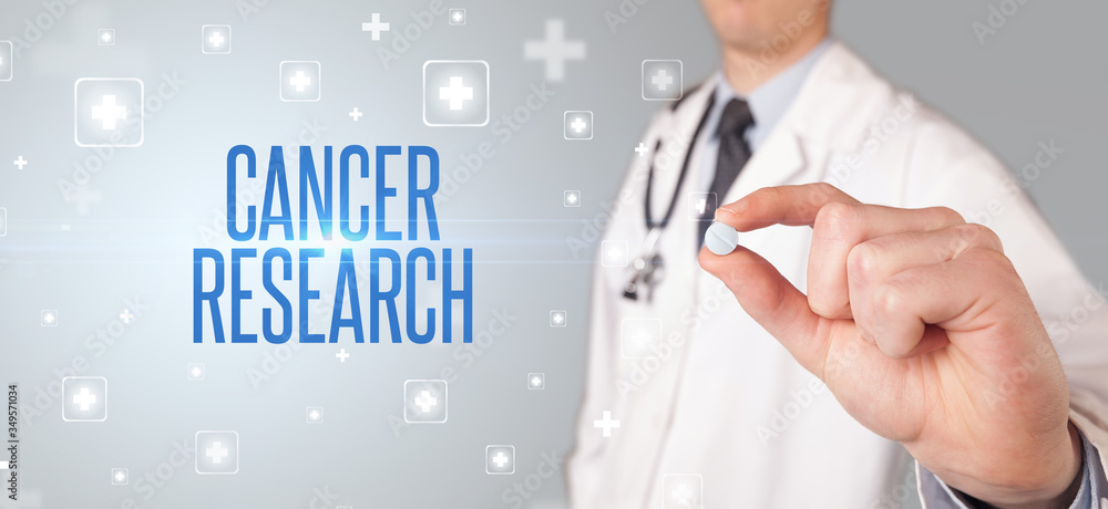 Close-up of a doctor giving a pill with CANCER RESEARCH inscription, medical concept Close-up of a doctor giving a pill with CANCER RESEARCH inscription, medical concept