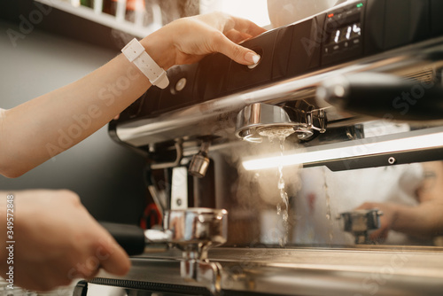 A female barista purging a grouphead thoroughly with hot water in the espresso machine in a coffee shop. A barista works in a cafe.