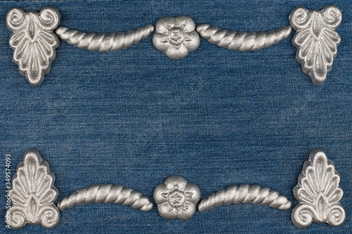 Frame made of silver-painted plaster molding lying on denim. Copy space. Top view.