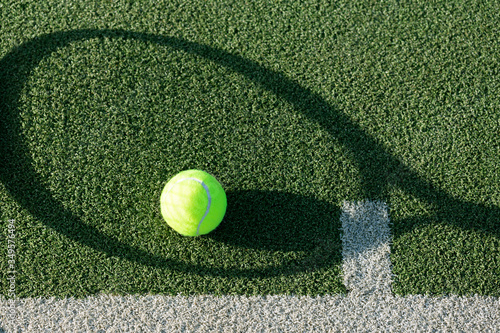 tennis racket shadow and tennis ball on it on a green grass kort. 