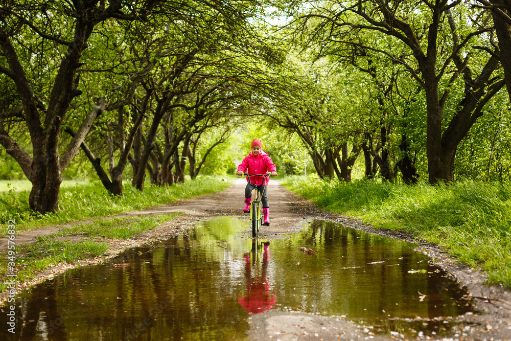 little girl riding bike in water puddle