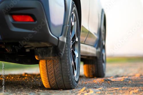 Close up of blue off road car wheel on gravel road. Traveling by auto, adventure in wildlife, expedition or extreme travel on a SUV automobile. Offroad 4x4 vehicle in field at sunrise.