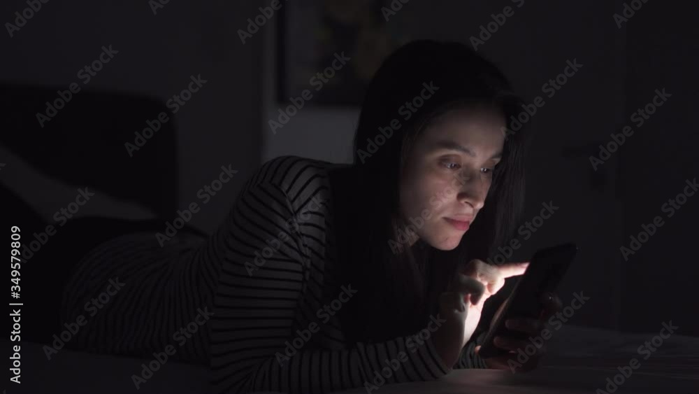 Woman is browsing social media in mobile phone at night on her bed
Woman is browsing social media in mobile phone at night on her bed