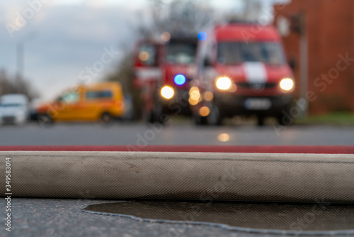 Fireman hose on the ground, in front of fire trucks