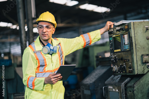 worker man caucasian in protective safety jumpsuit uniform and with hardhat and using digital tablet at factory.Metalworking industry concept professional engineer in tool manufacturing workshop