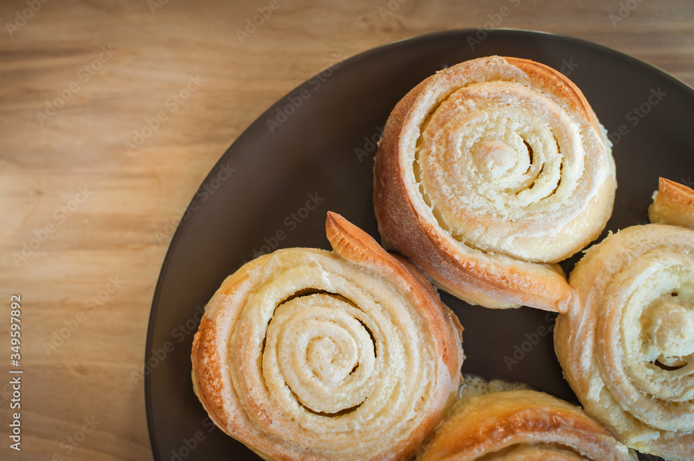 Freshly baked buns with cream on a brown plate wooden background. View from above .