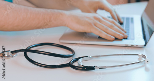 Foto Mani medico che scrive tastiera laptop